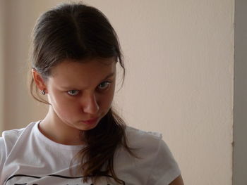 Portrait of woman making face against wall at home