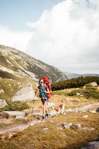 Rear view of man walking on mountain against sky