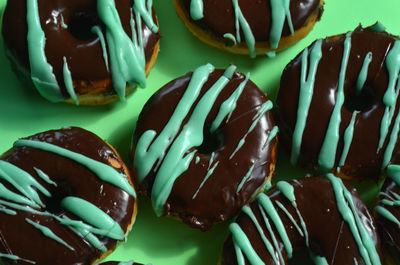 Donuts with chocolate frosting and stripes of green frosting on green paper