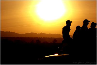 Silhouette people on mountain at sunset