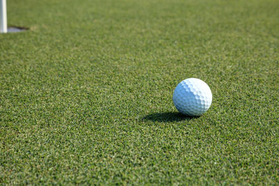 Golf ball and flag on lush green grass on a golf course