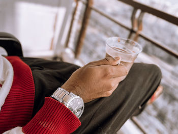 Midsection of man holding glass while sitting on table