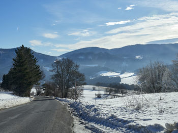 Road by snowcapped mountains against sky