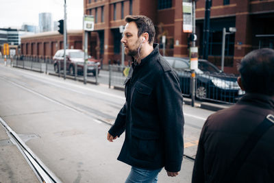 Full length of man and woman walking on street in city