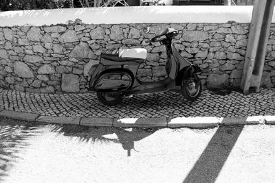 Motor scooter parked on sidewalk against surrounding wall