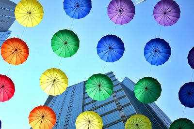 Low angle view of multi colored umbrellas hanging against sky