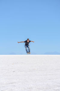 Full length of woman with arms raised against clear sky