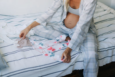 Pregnant woman preparing newborn's clothes at home