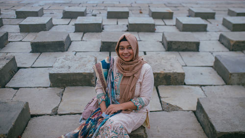 Portrait of a smiling young woman sitting on staircase