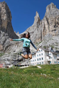 Full length of man on rocks by mountains against clear sky