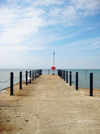 Pier on sea against cloudy sky