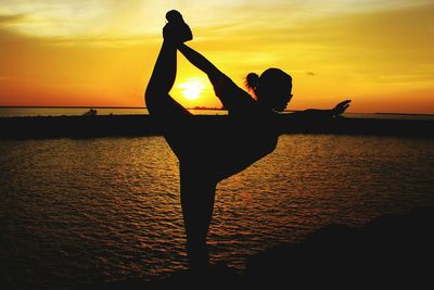 Silhouette man in sea against sky during sunset