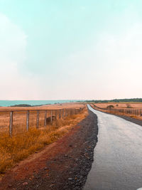 Road amidst land against sky