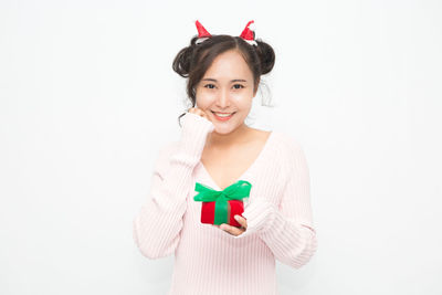 Portrait of young woman standing against white background