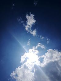 Low angle view of sunlight streaming through clouds