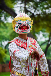 Midsection of man wearing red mask against plants