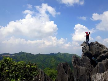 Man standing on cliff against sky