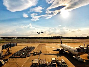 Airplane flying over airport runway against sky