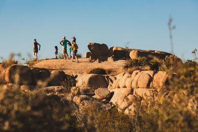 Group of people on rock against clear sky