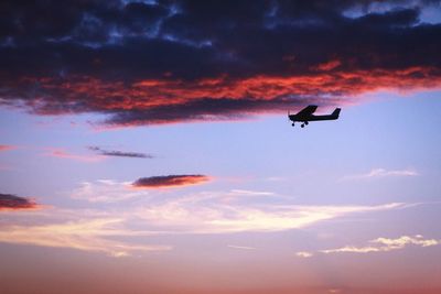 Low angle view of airplane against cloudy sky