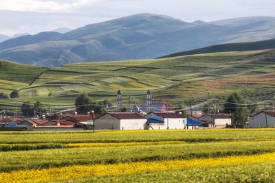 Scenic view of agricultural field by houses and mountains