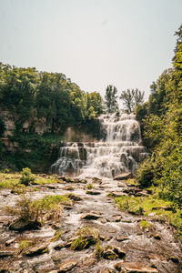 Scenic view of waterfall in forest against sky