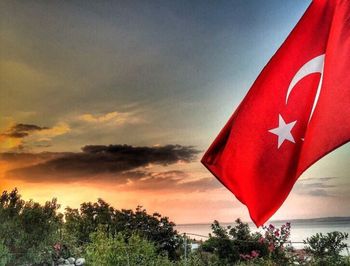 Scenic view of red flag against sky during sunset