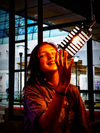 Portrait of smiling woman standing against window