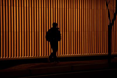 Rear view of silhouette man standing against wall