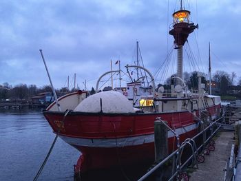 Sailboats moored at harbor against sky