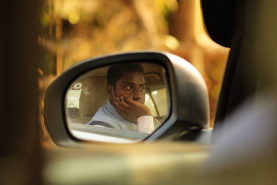 Reflection of man in side-view mirror of car