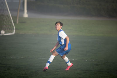 Teen soccer player ready to defend on a foggy field