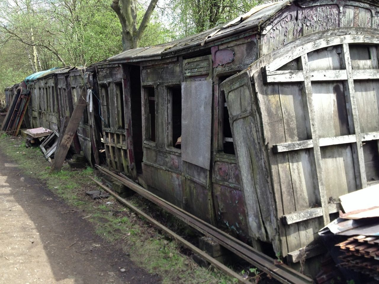 built structure, architecture, building exterior, transportation, abandoned, mode of transport, old, obsolete, tree, damaged, house, land vehicle, railroad track, run-down, deterioration, day, outdoors, rail transportation, car, weathered