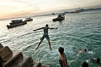 Rear view of boy jumping in sea