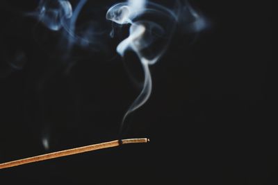 Close-up of incense stick against black background