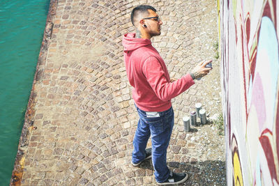 Full length of man spraying graffiti on wall