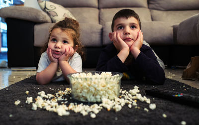 Siblings watching a home movie while eating popcorn