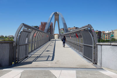 People walking in modern city against clear blue sky