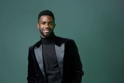 Portrait of young man standing against black background