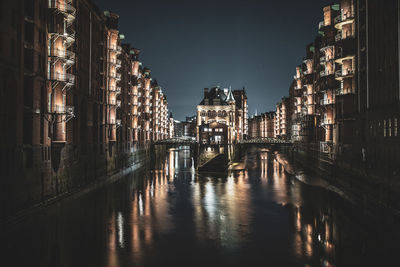 Canal amidst illuminated buildings in city at night