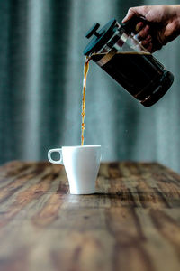 Cropped image of man pouring coffee in cup on table