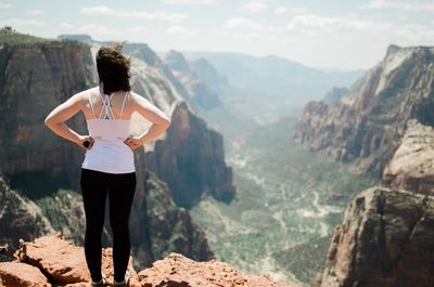 Woman standing on rock while looking at mountains