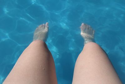 Low section of person relaxing in swimming pool