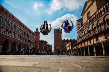 Surface level shot of men backflipping on street outside ferrara cathedral