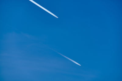 Low angle view of airplane flying against blue sky