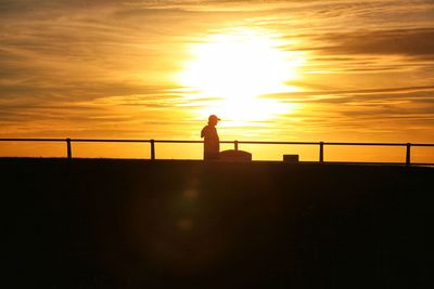 Low angle view of silhouette man standing on bridge against sky during sunset