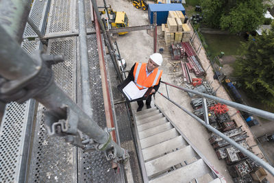 Man wearing safety vest on scaffolding on construction site