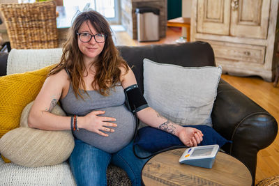 Young woman using mobile phone while sitting on sofa at home