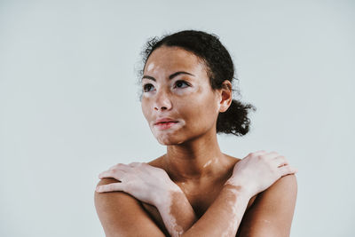 Close-up of woman looking away against colored background