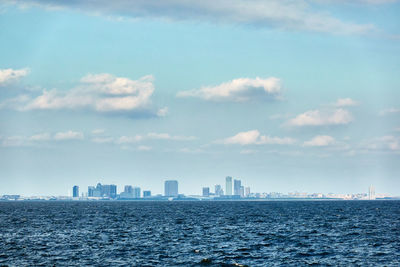 Sea by buildings against sky in city